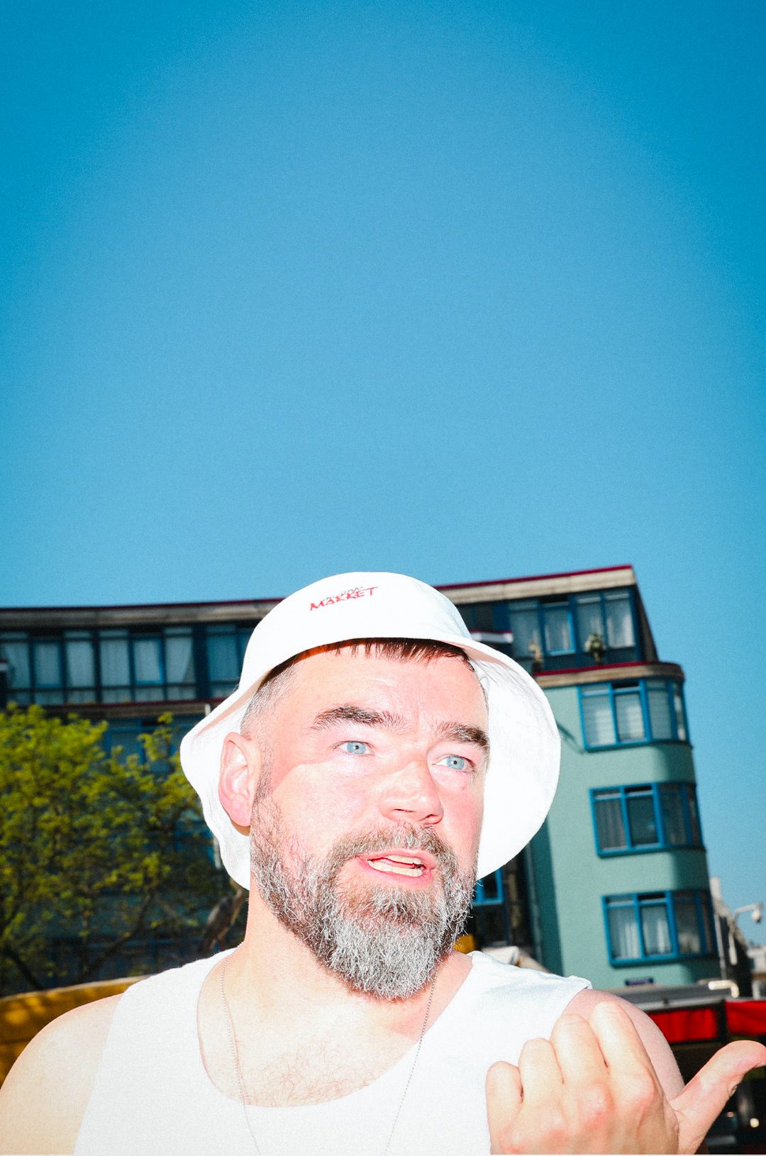 Man in a white .market bucket hat against a blue sky