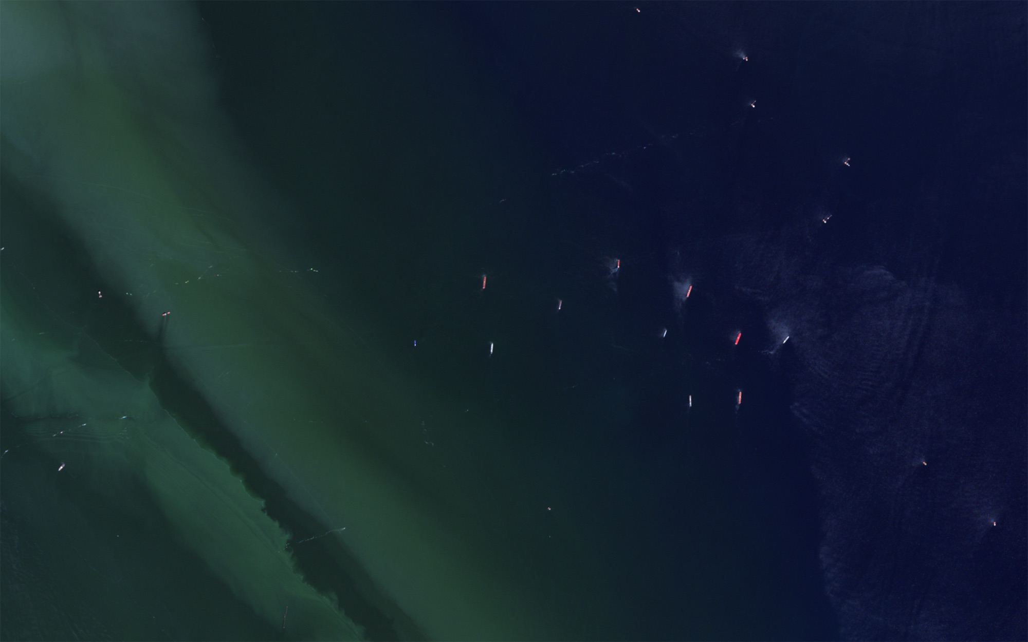Ships scattered where green sediment meets deep blue sea