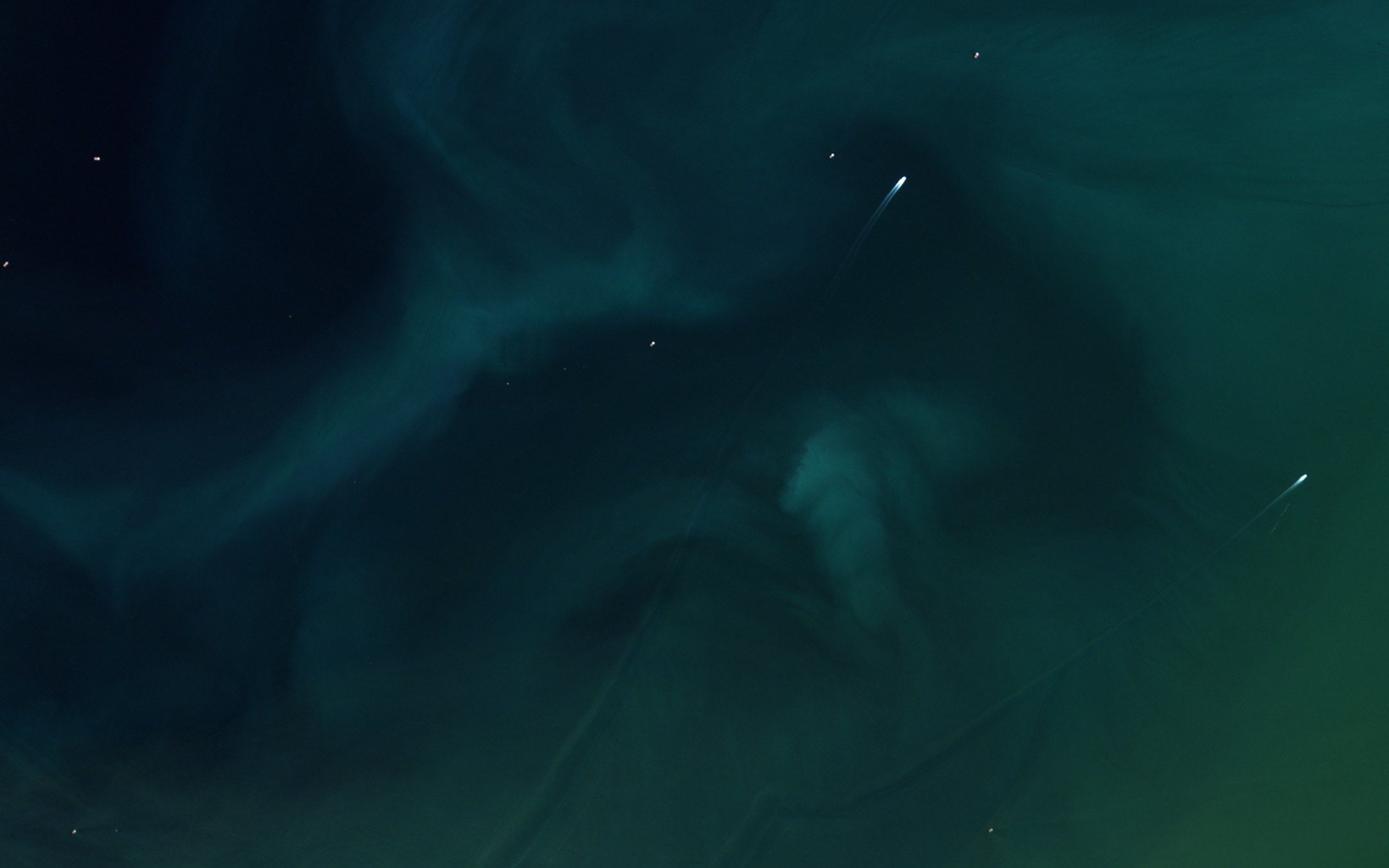 Boat wakes like streaks of light across dark swirling water
