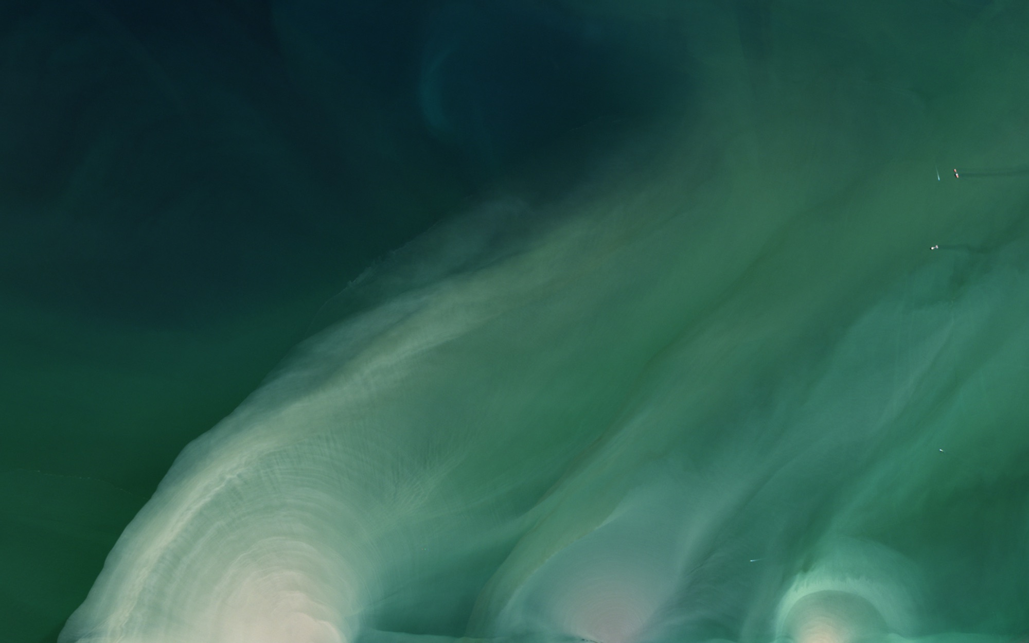 Pale sediment fanning out into deep green water