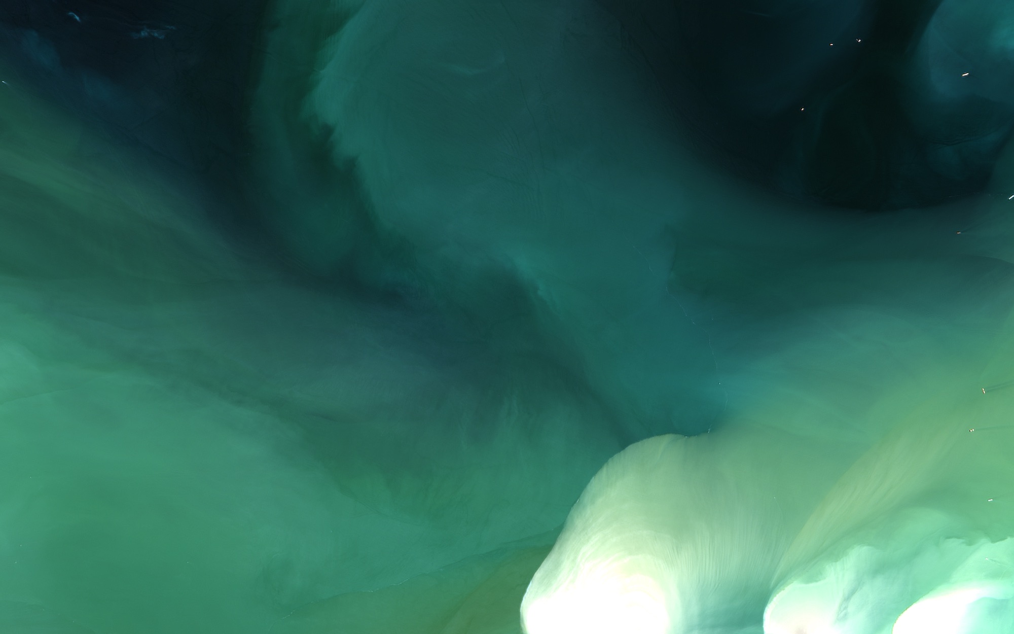 Teal water with white plumes rising at the lower right