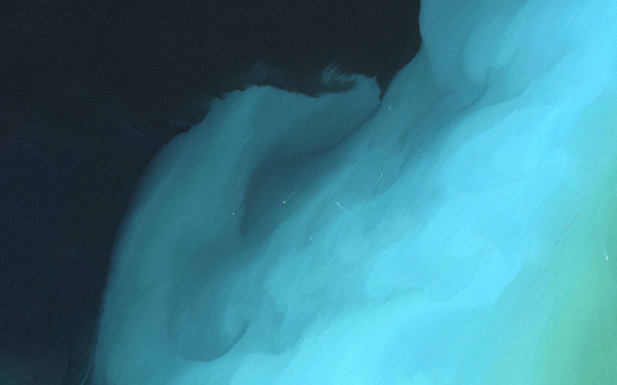 A wall of cyan sediment pressing into dark open sea
