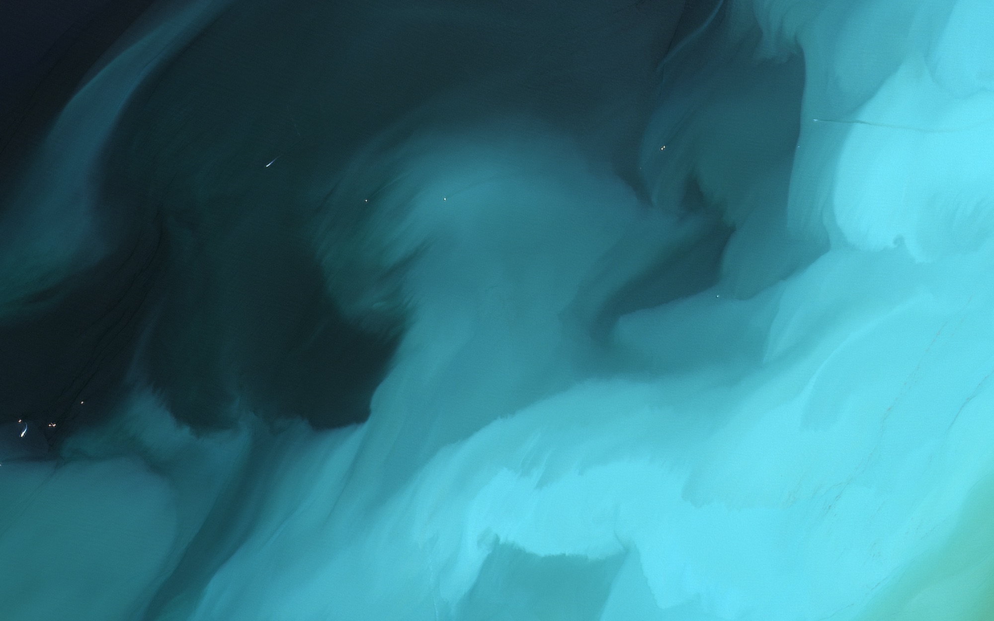 Swirls of bright cyan sediment against dark water