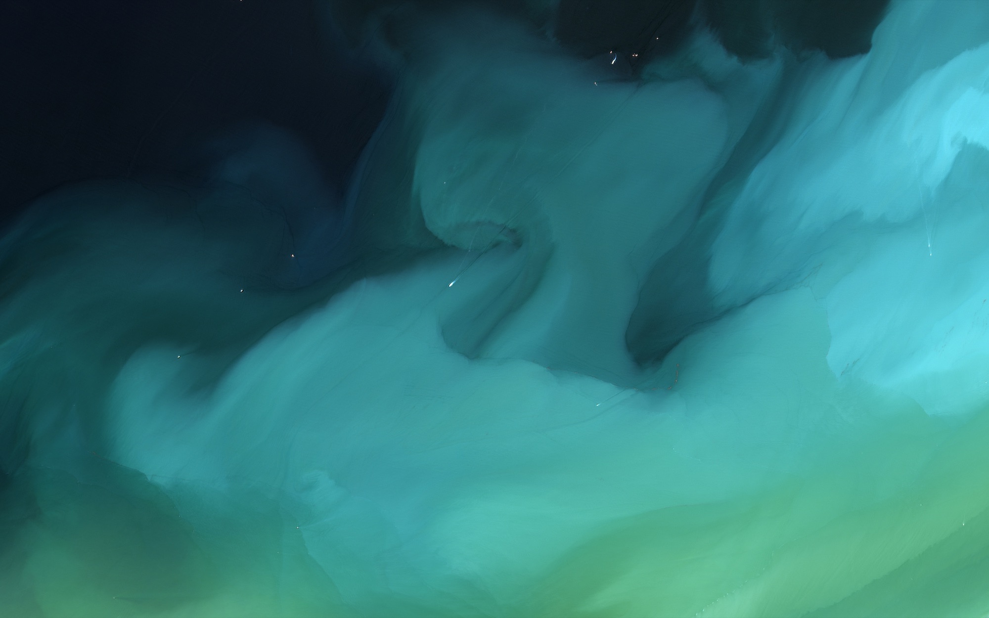 Teal sediment folding over itself, green water below